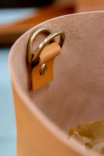 A tan coloured leather bag with solid brass d-rings and a chicago screw inserted