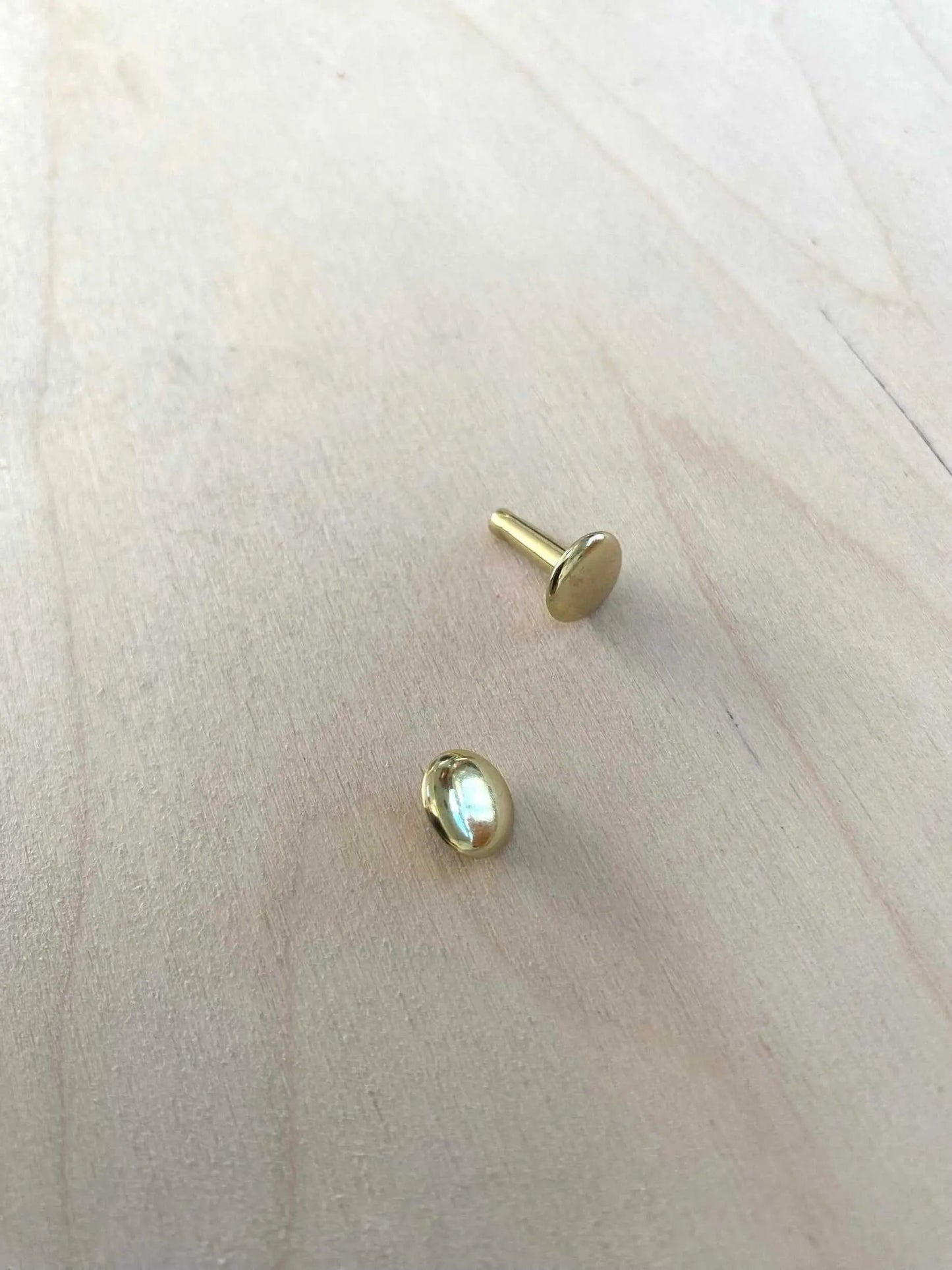 Solid Brass Double Cap Leather Rivets on wooden surface, showcasing durable and stylish design for crafting projects.