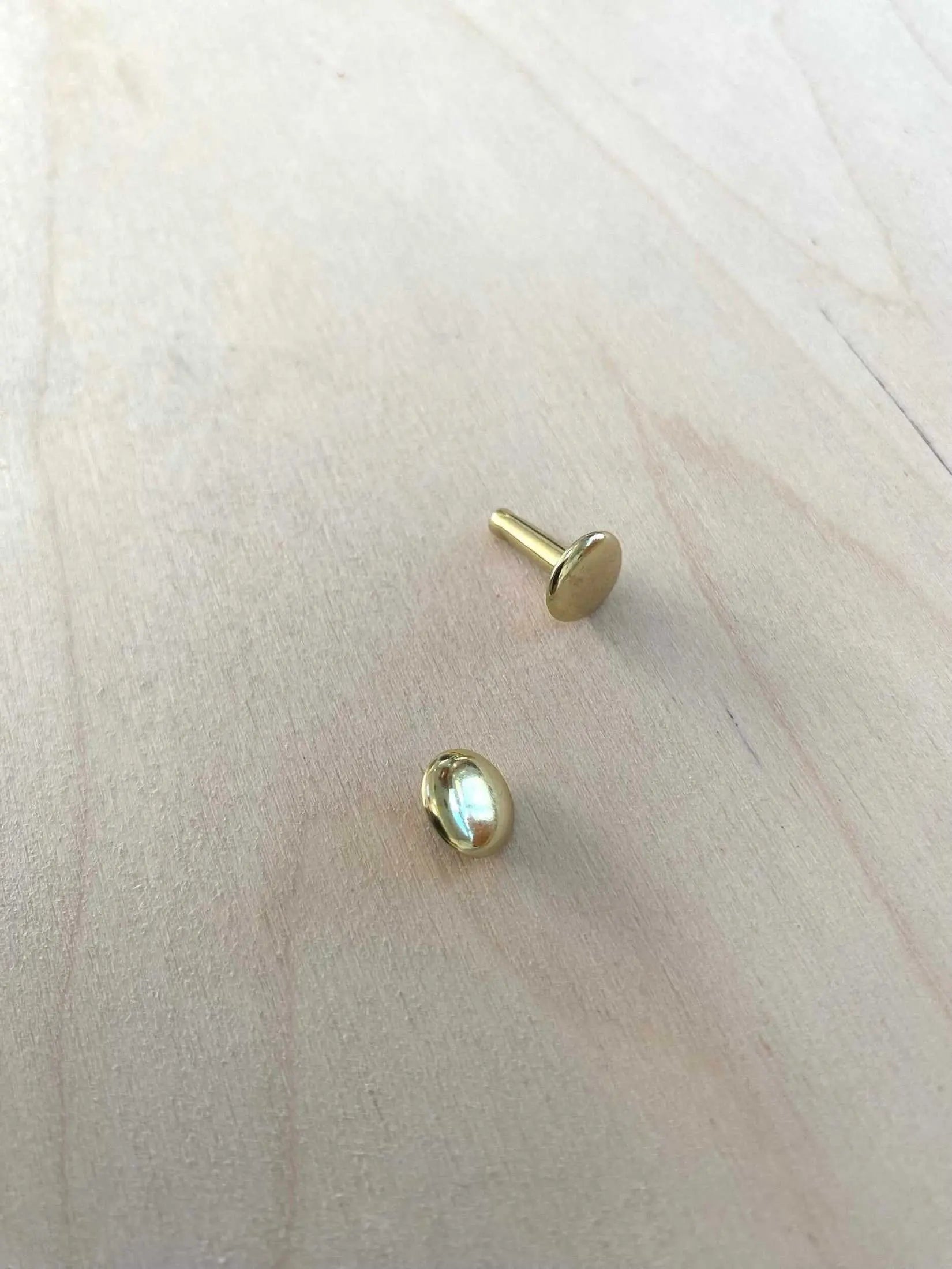 Solid Brass Double Cap Leather Rivets on wooden surface, showcasing durable and stylish design for crafting projects.