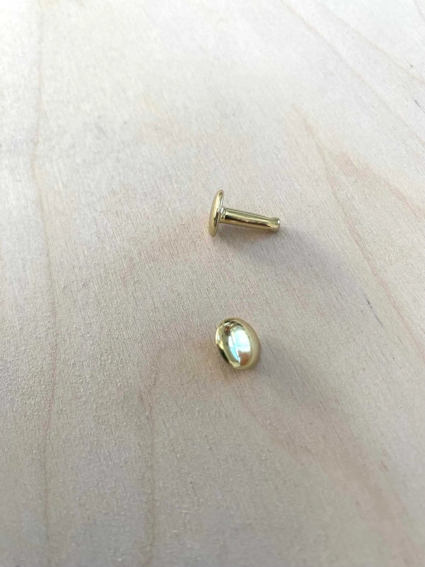 Solid Brass Double Cap Leather Rivets on wooden surface, showcasing durability and elegance.