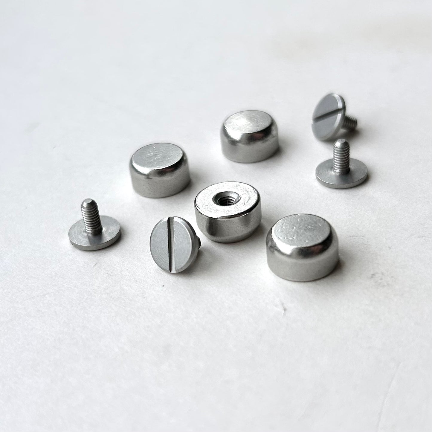 Set of metal screw bag feet in silver on a white background