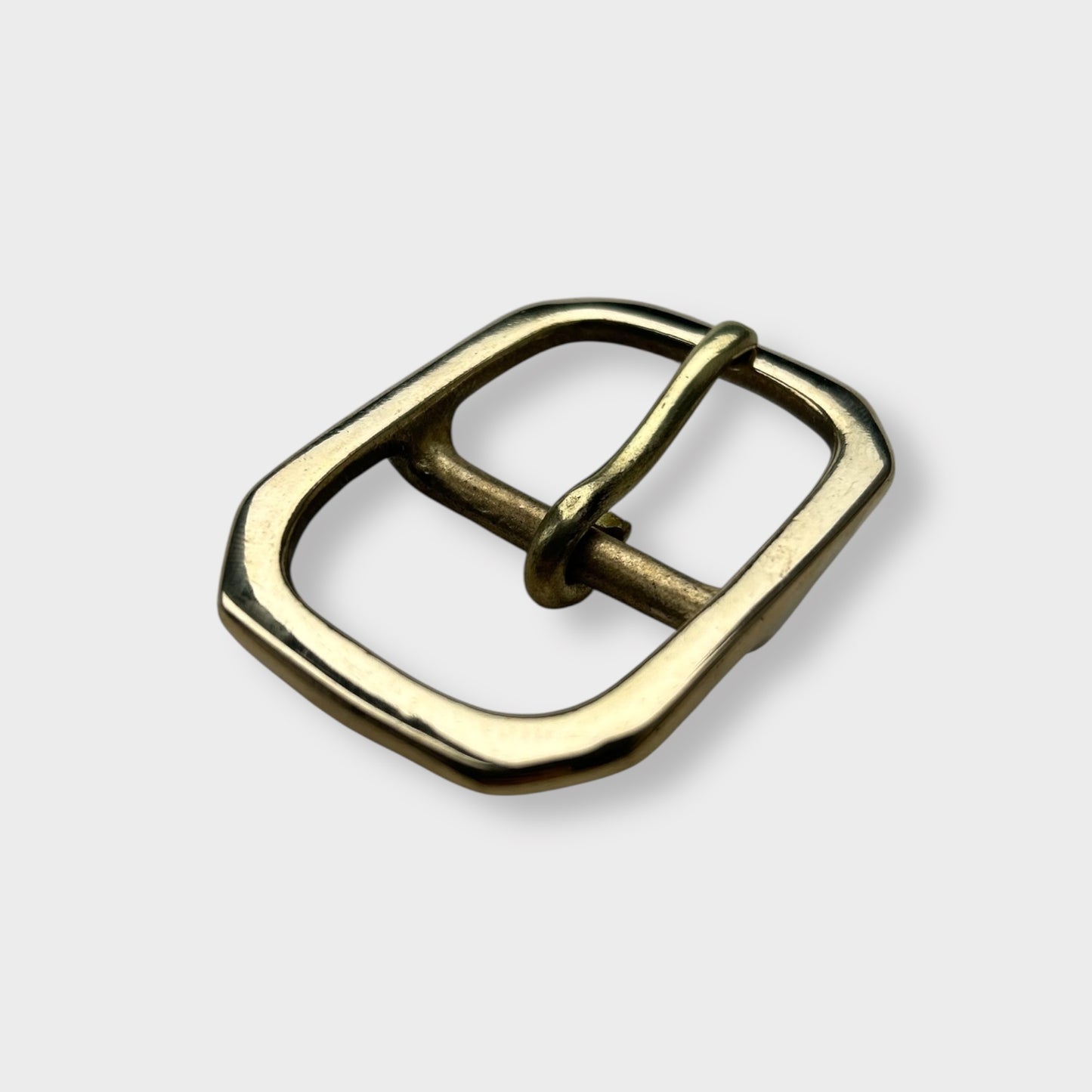 Gold coloured brass metal buckle with a centre bar on a light grey background.