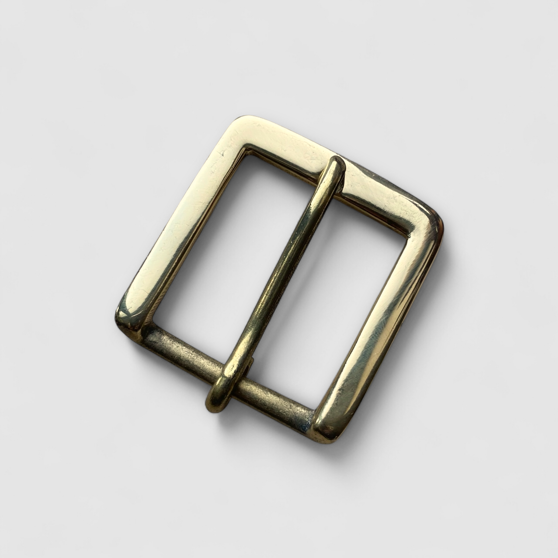 Brass metal buckle on a light grey background