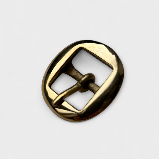 Gold coloured metal brass buckle on a light grey background