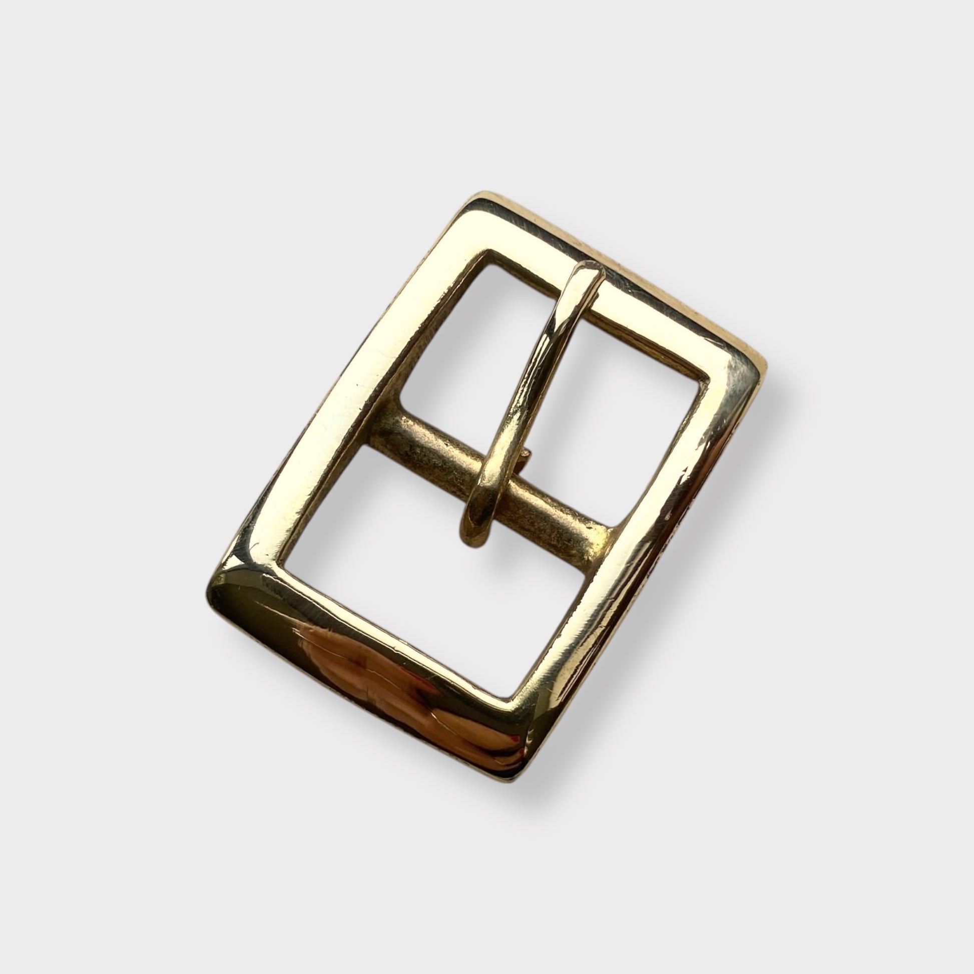 Brass buckle in a square frame centre bar style on a grey background.