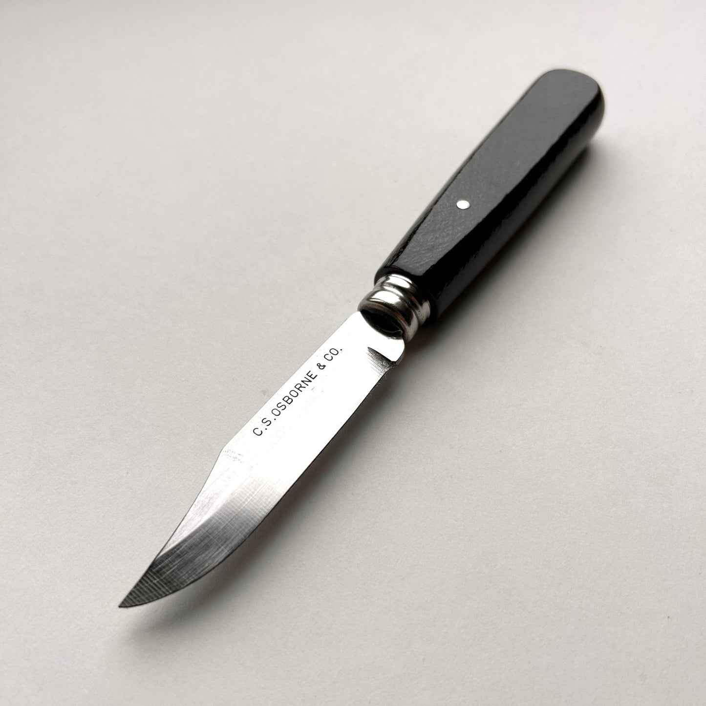 Knife with a black handle and silver blade on a light gray background