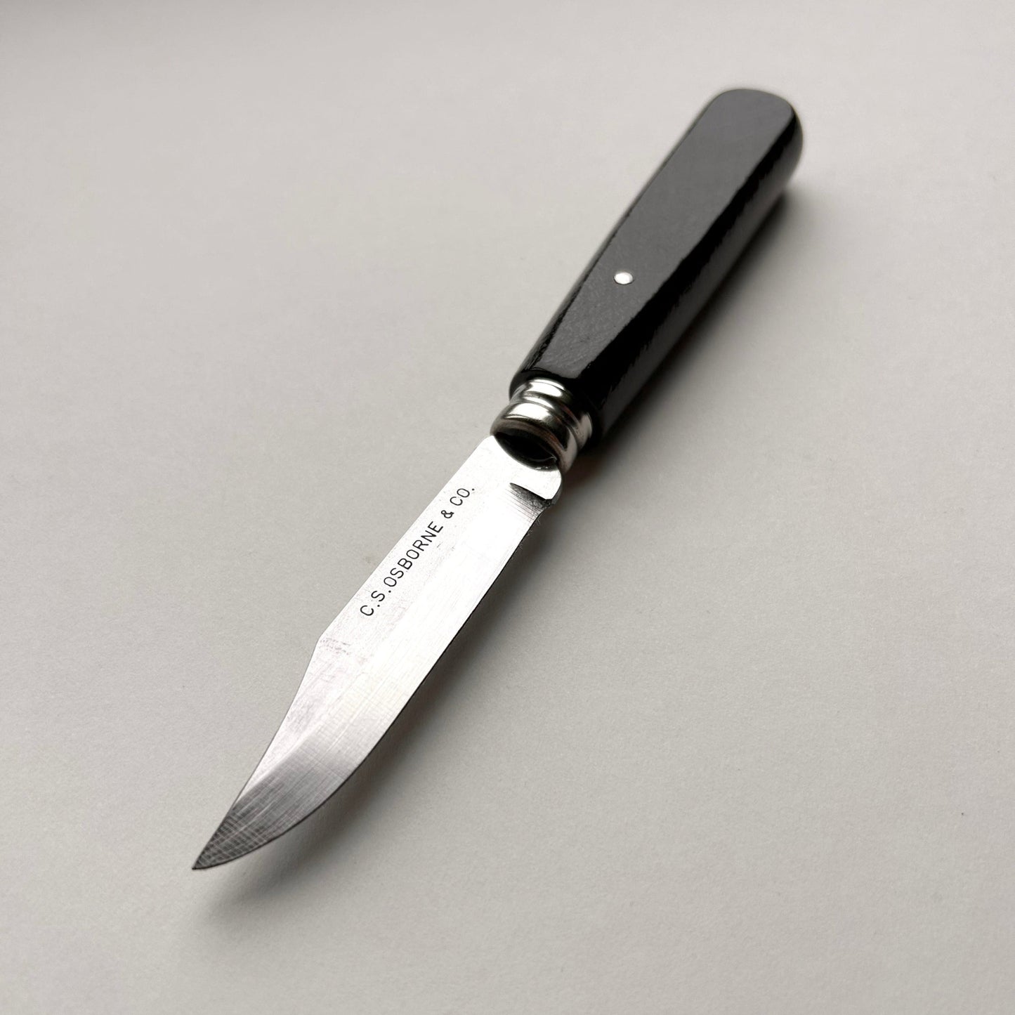 Black-handled knife with a silver blade on a gray background