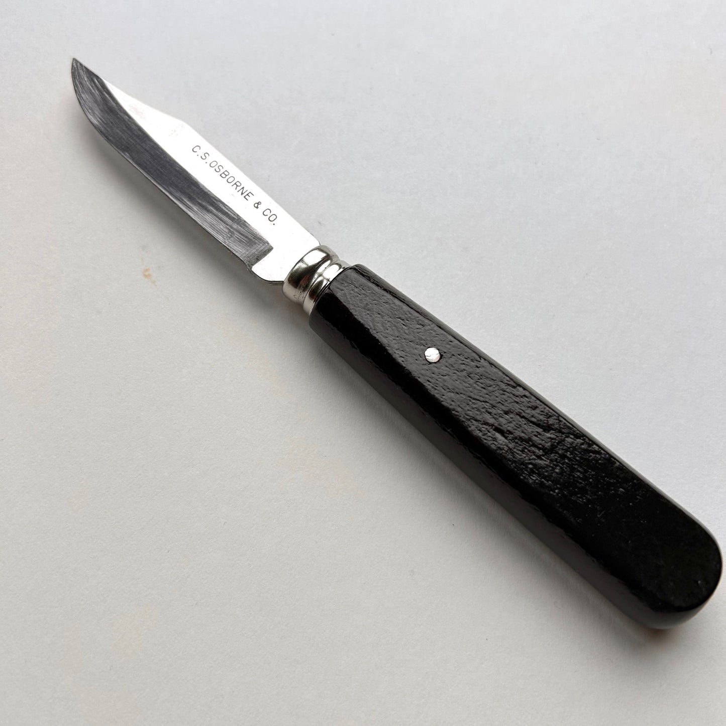 Knife with black handle and silver blade on a light gray background