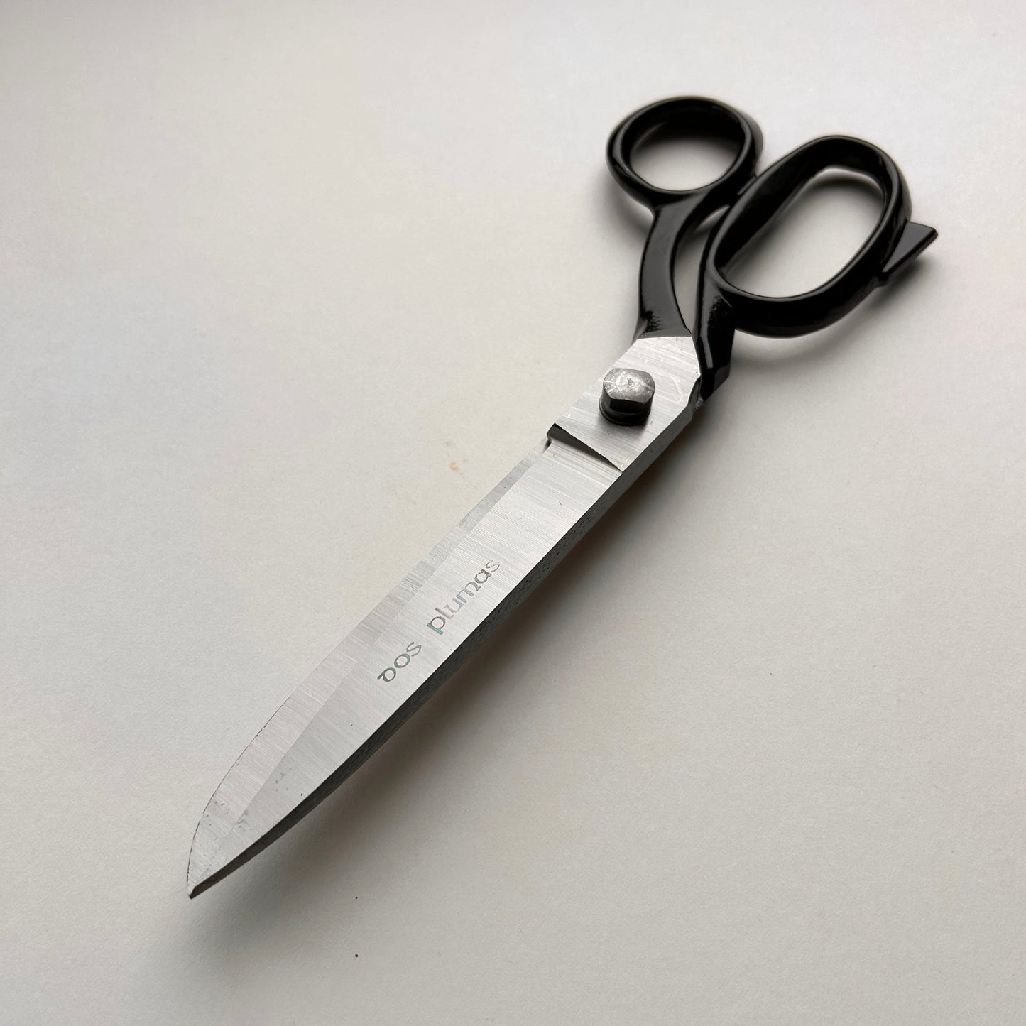 Pair of leather scissors with black handles on a white background