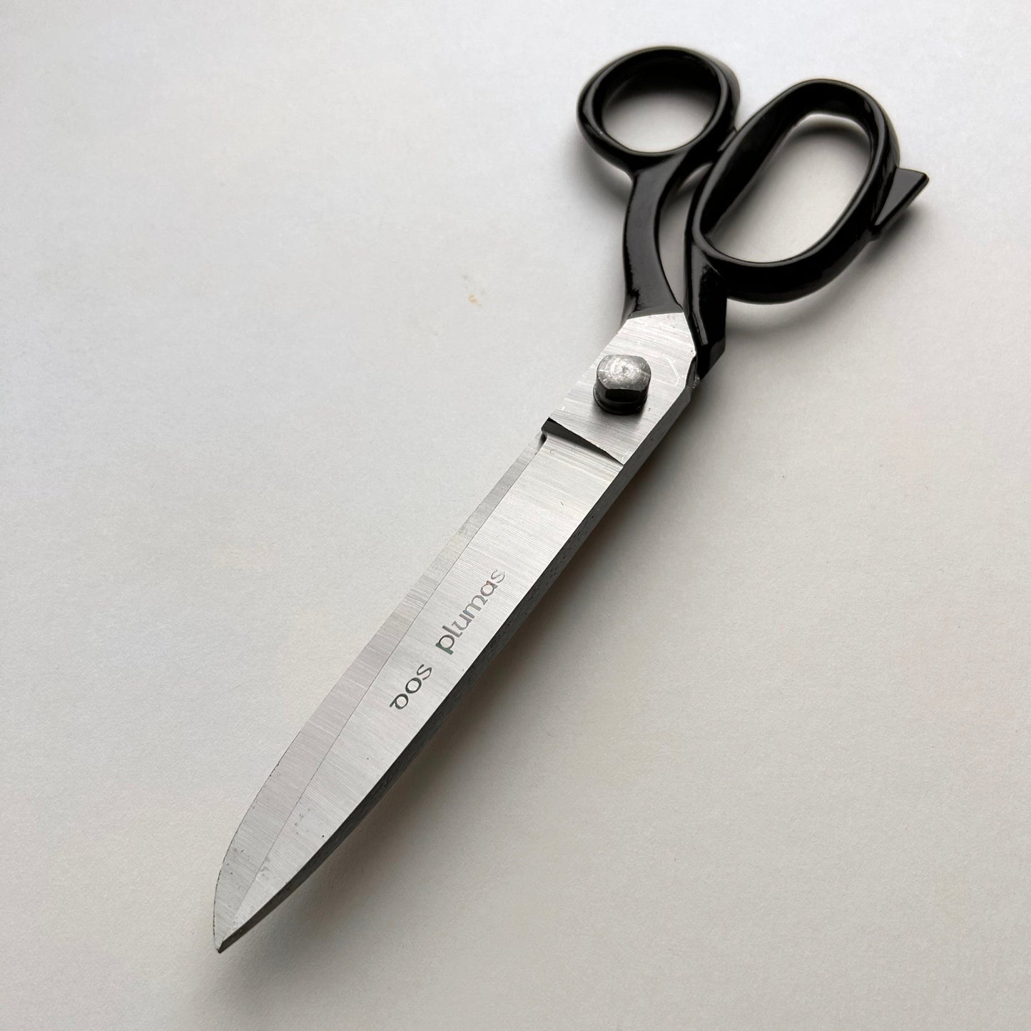 Pair of leather scissors with black handles on a white background