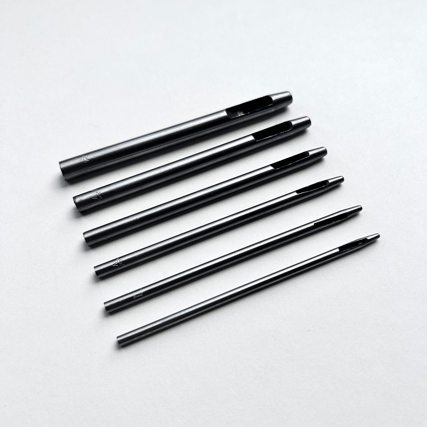 Set of six leather hole punch tools on a white background