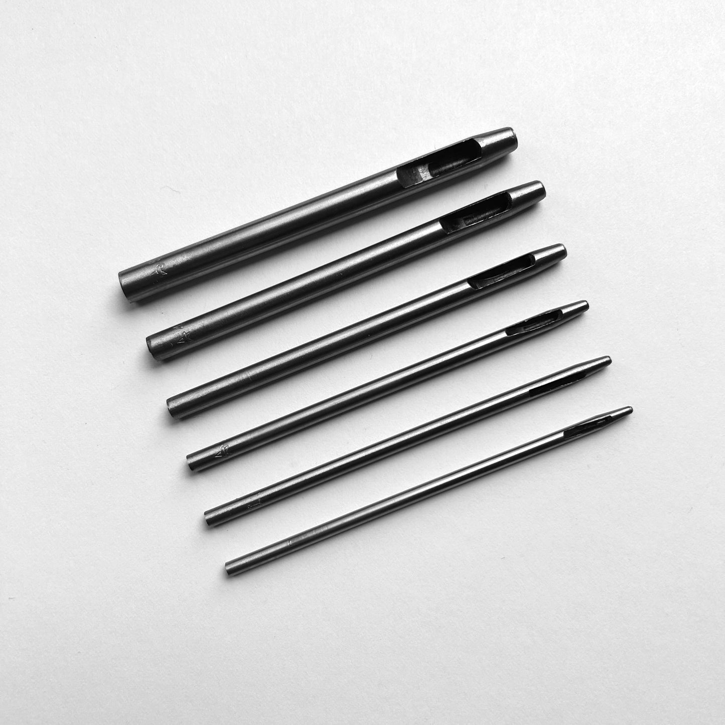 Set of six leather hole punch tools on a white background