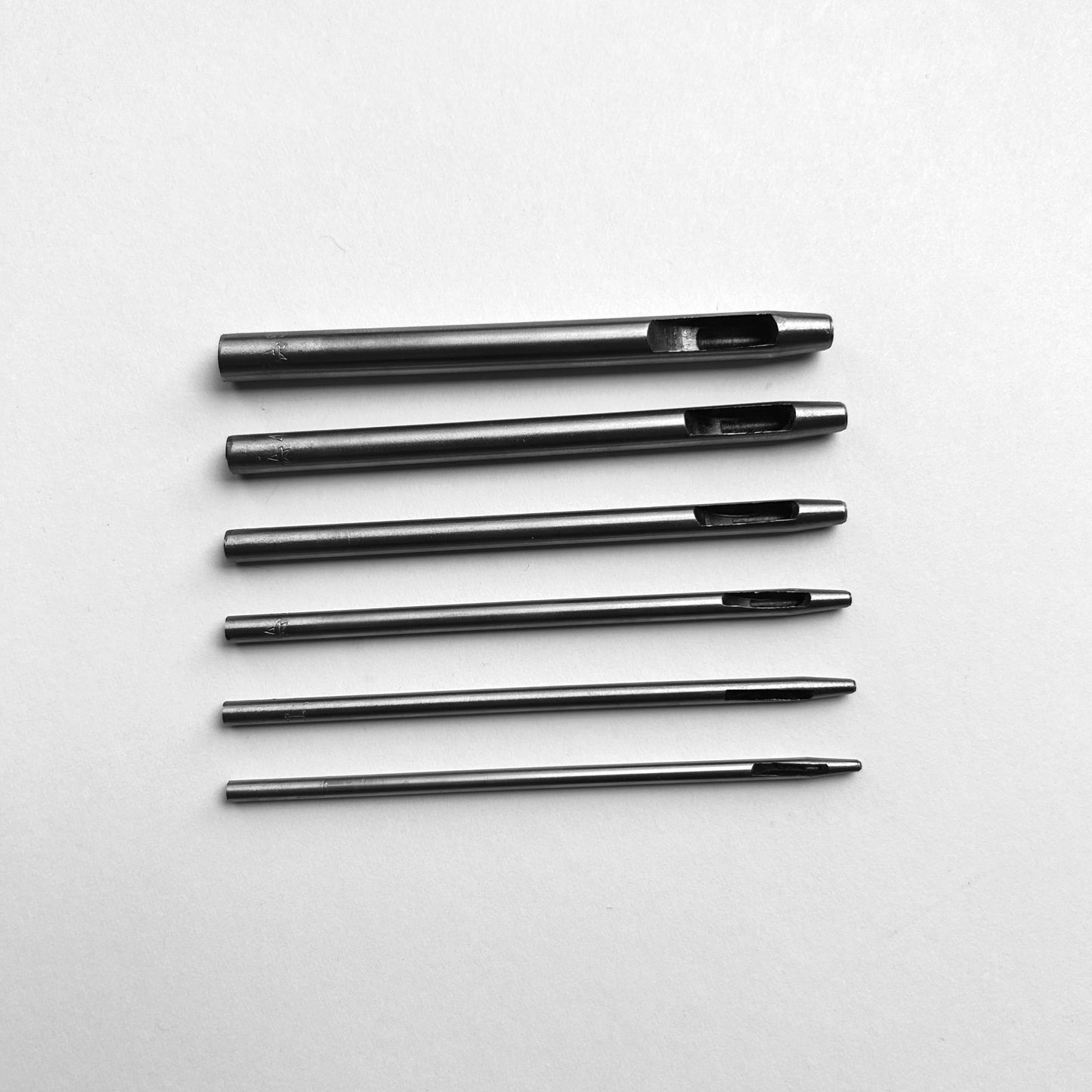Set of six leather hole punch tools on a white background