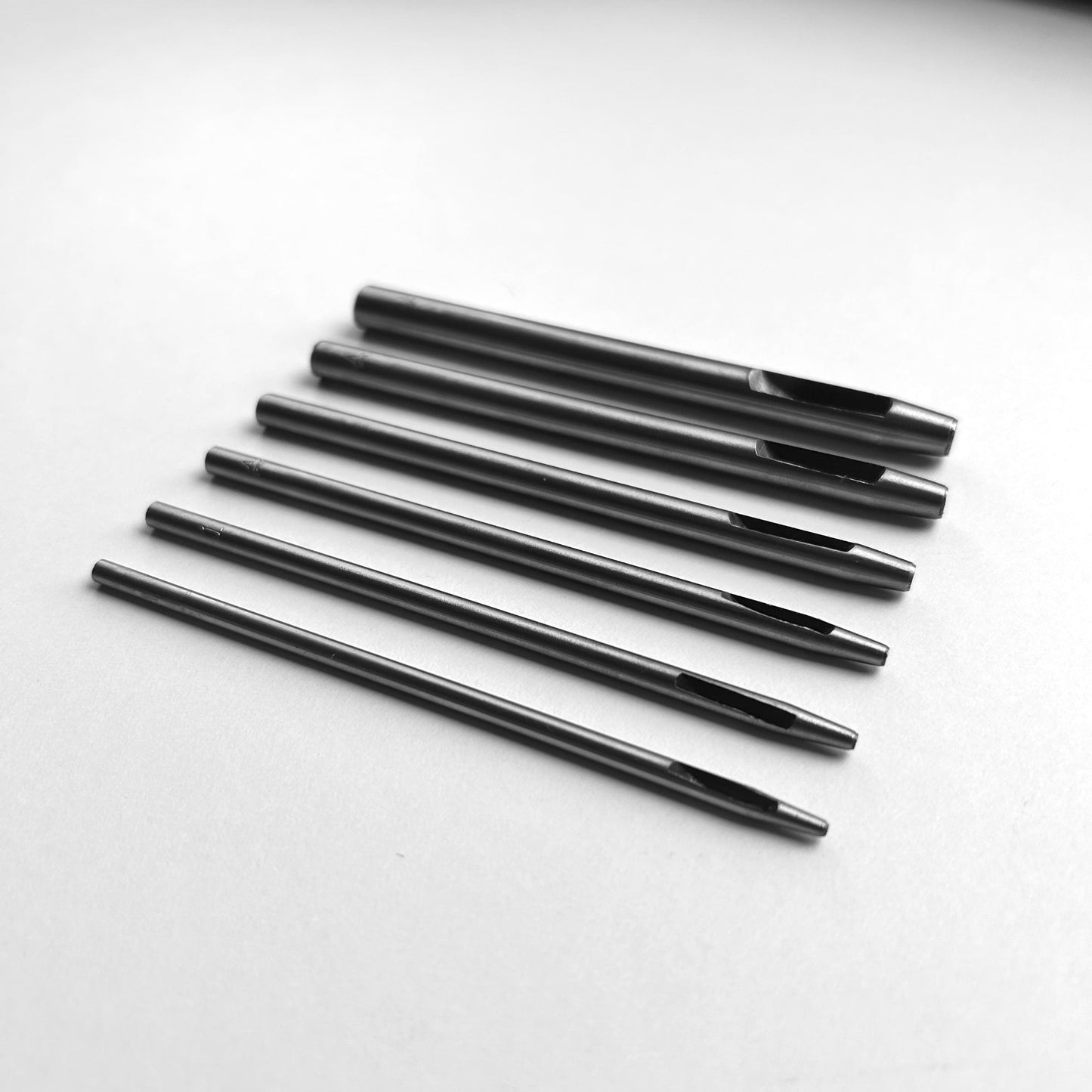 Set of six leather hole punch tools on a white background