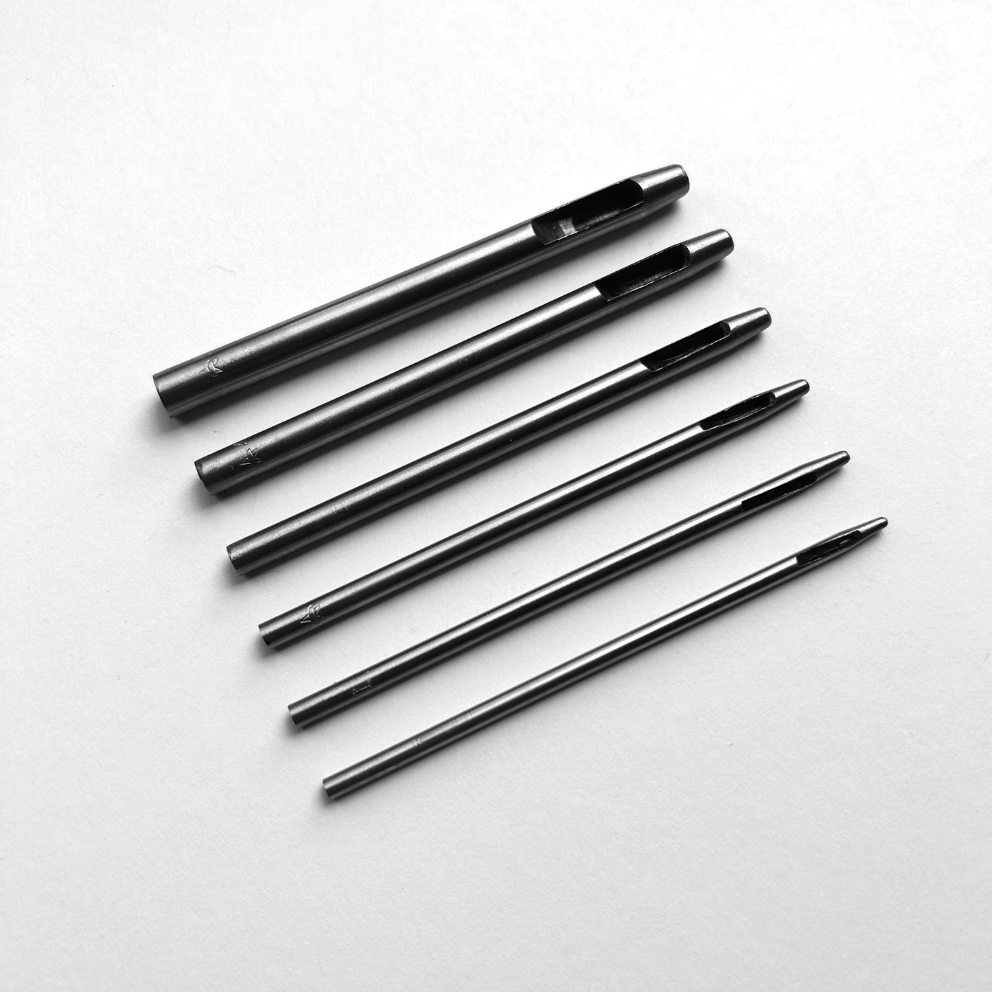 Set of six leather hole punch tools on a white background