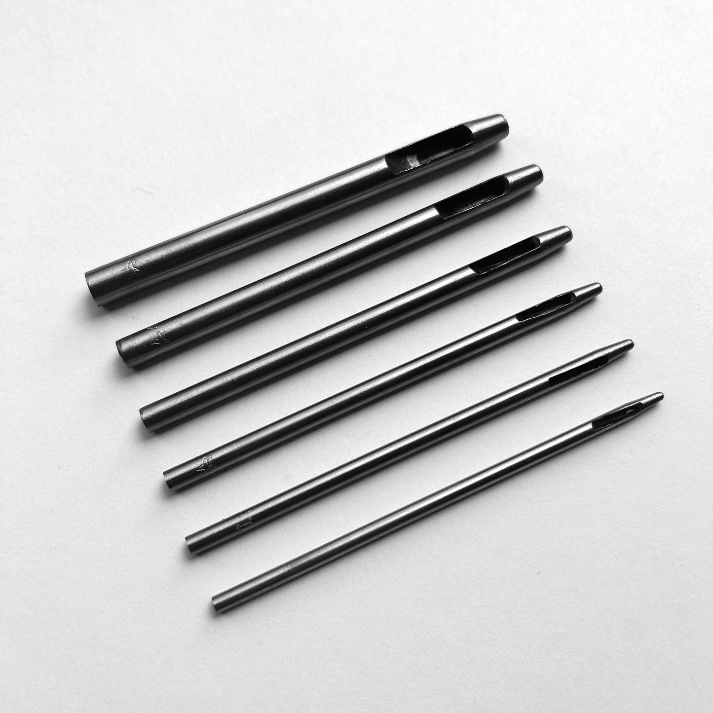 Set of six leather hole punch tools on a white background