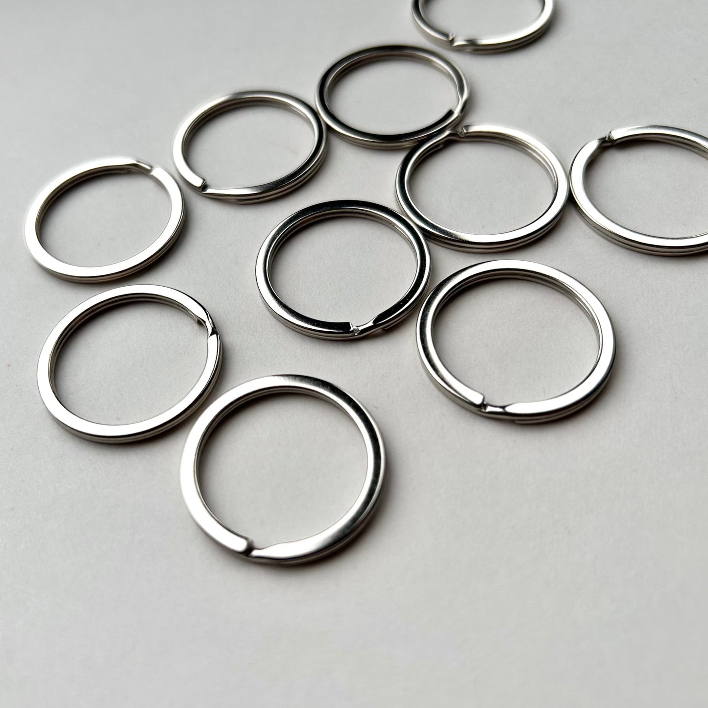 Multiple silver keyrings on a grey background
