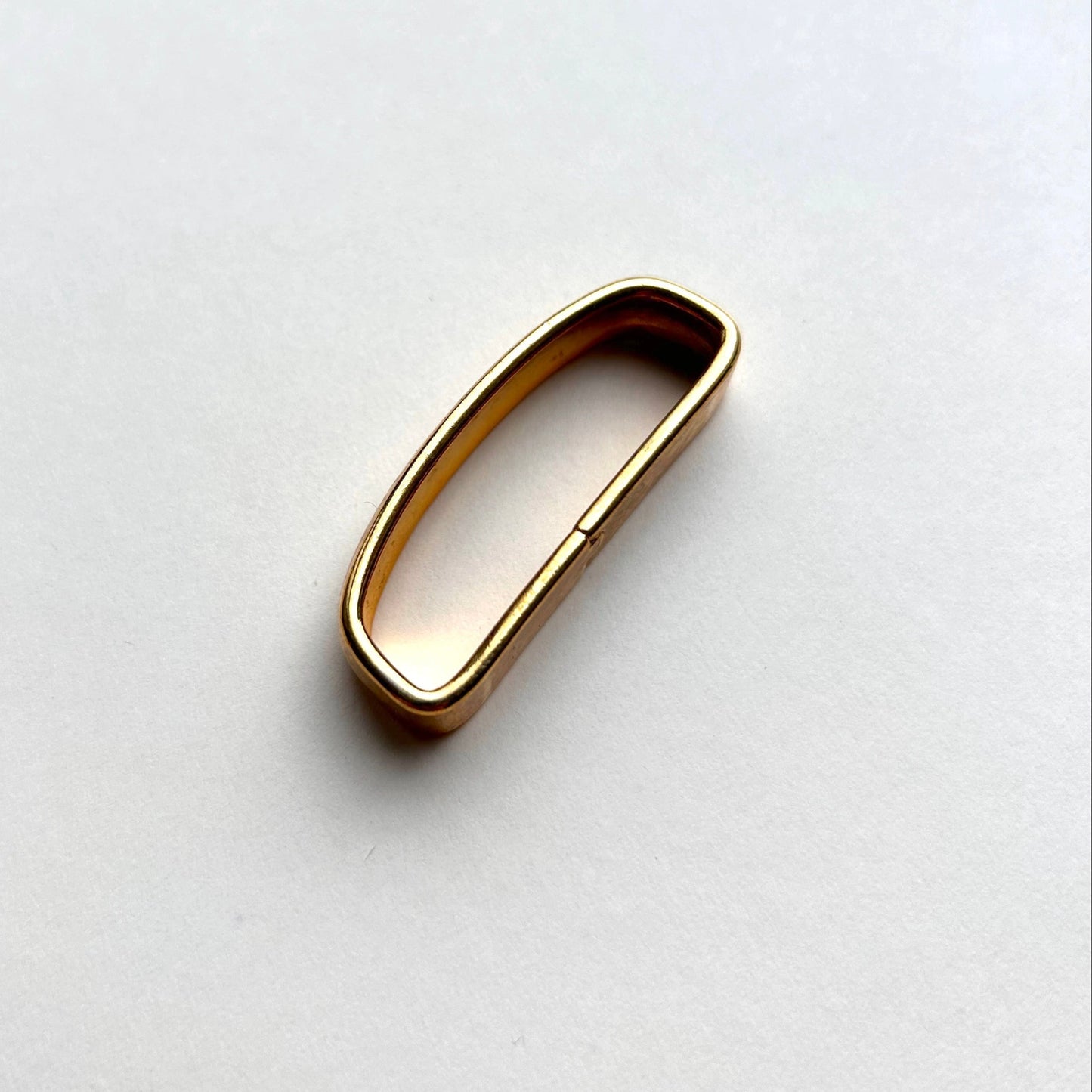 Solid brass gold belt loop keeper on white background