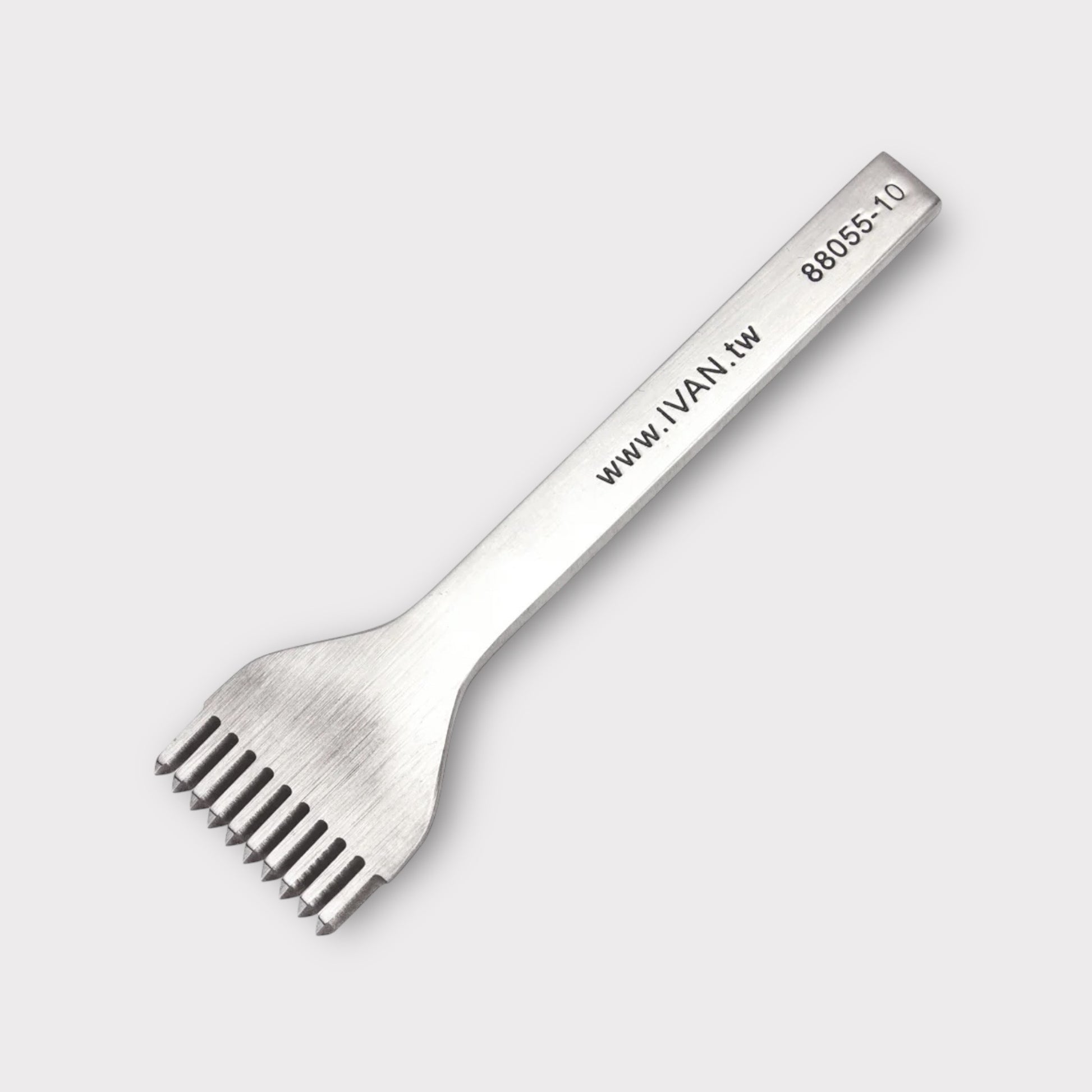 Stainless steel leather stitching punch with engraved IVAN text on a light grey background
