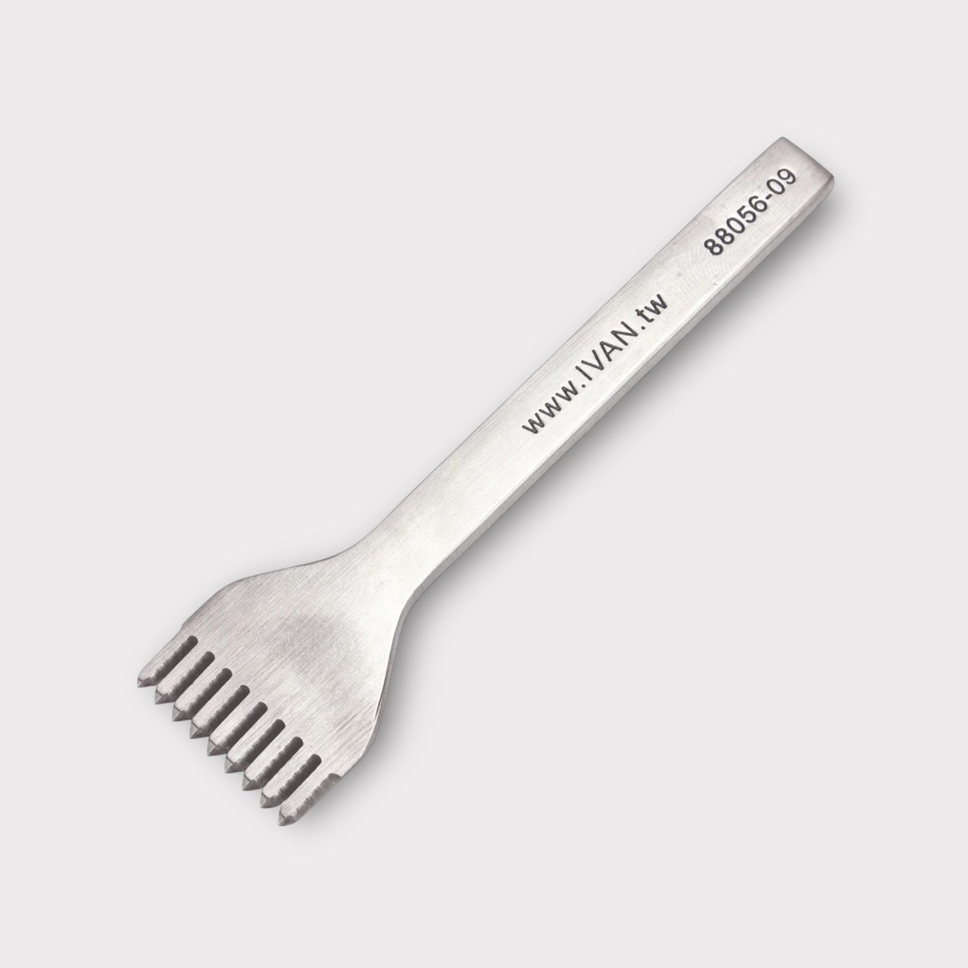 Stainless steel leather stitching punch with engraved IVAN text on a light grey background