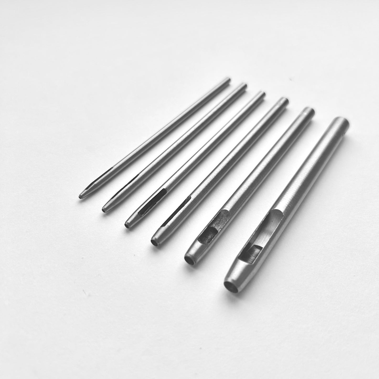Set of six silver leather drive punches on a white background