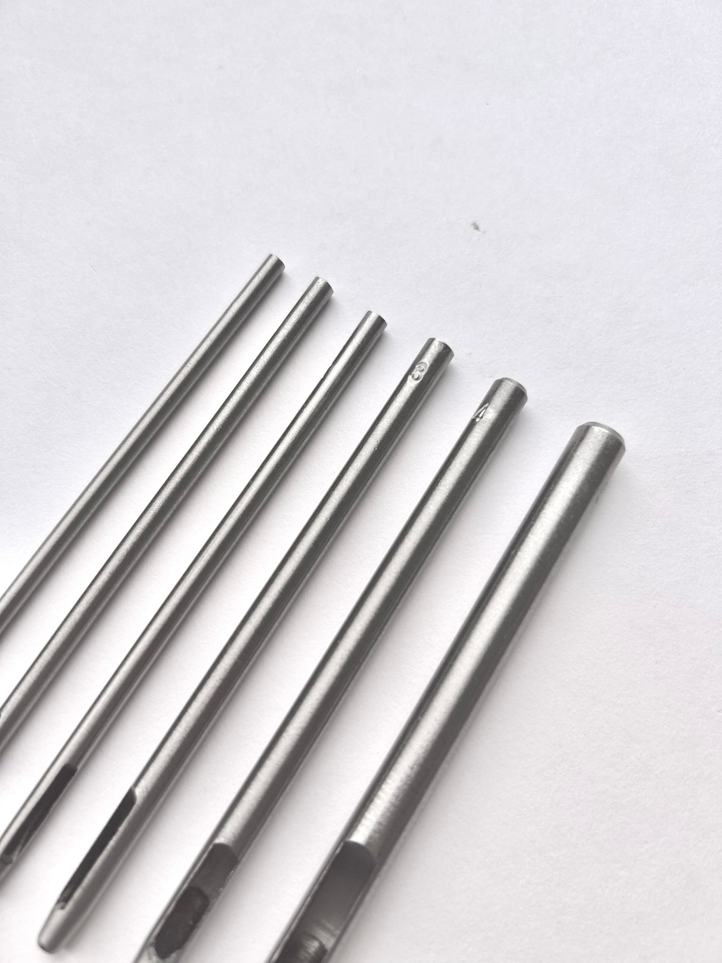 Set of six silver leather drive punches on a white background