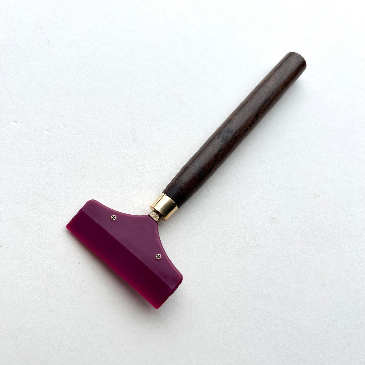Leather glue spreader tool with purple blade and black wooden handle on a white background