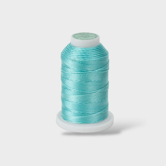 Spool of turquoise thread on a light gray background