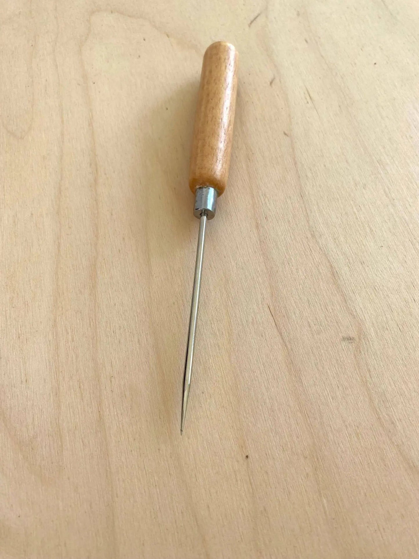 Long Handle Leather Scratch Awl for leatherworking on wood surface, showcasing craftsmanship and precision.