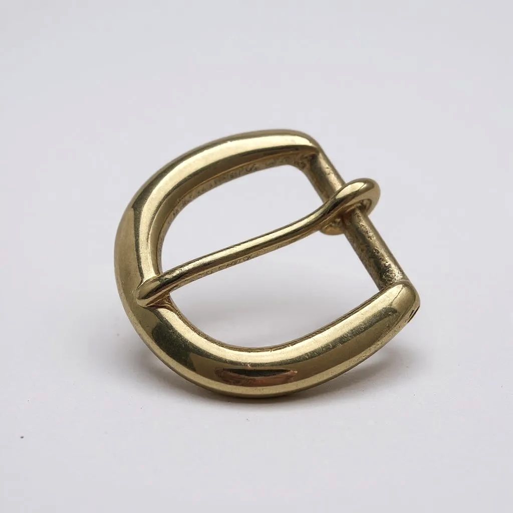Brass buckle d shaped saddlery style on white background