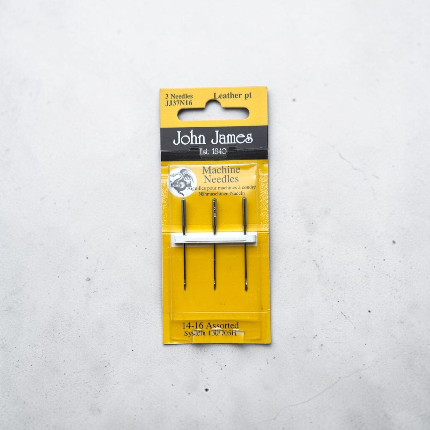 Packaged John James sewing machine needles on a grey background