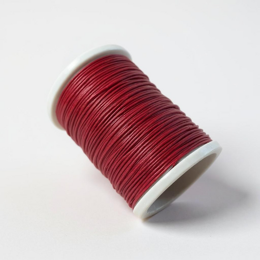 Spool of red thread for hand stitching leather on a white background