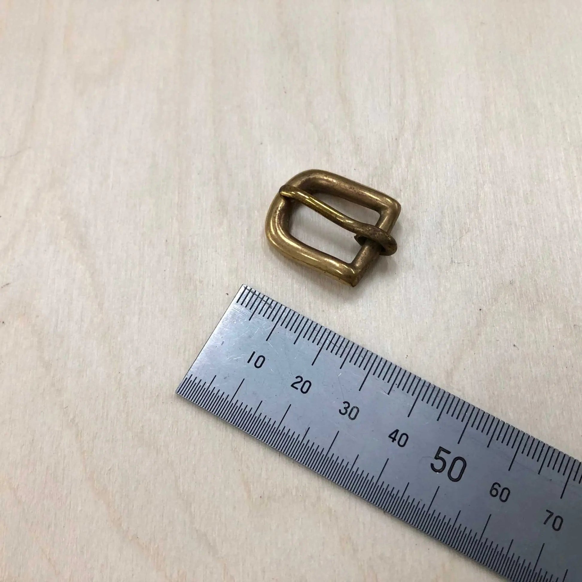 Solid Brass Buckle next to a ruler for size reference, showcasing its rounded frame and pin style.