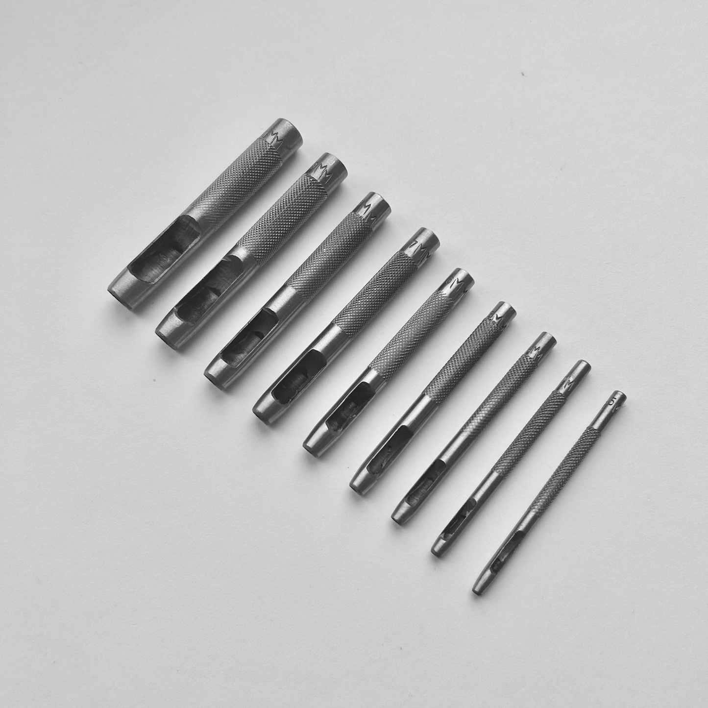 Set of metal leather drive punch tools on a grey background