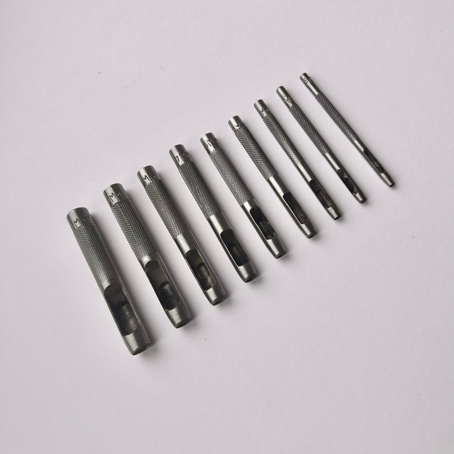 Set of metal leather drive punch tools on a grey background