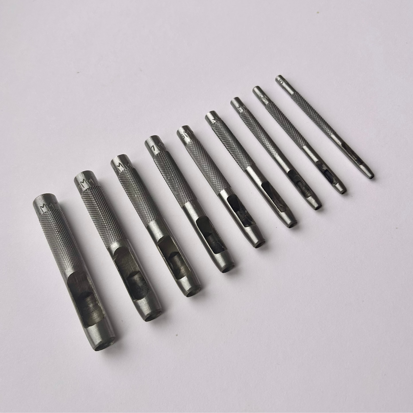 Set of metal leather drive punch tools on a grey background