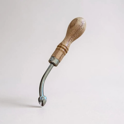 Wooden-handled adjustable leather edge creaser tool on a light grey background
