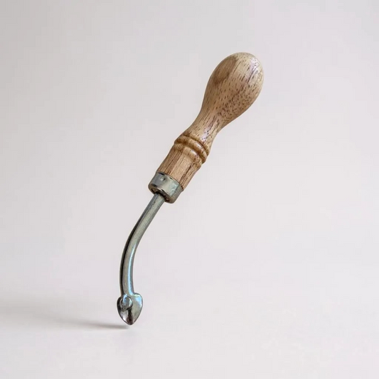 Wooden-handled adjustable leather edge creaser tool on a light grey background