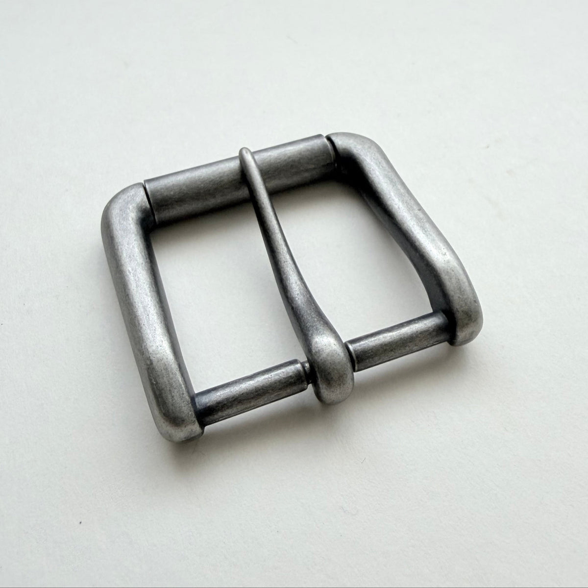 A single metallic buckle with a square-shaped frame and a central pin, shown on a plain light background.