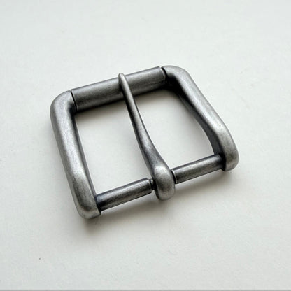 A single metallic buckle with a square-shaped frame and a central pin, shown on a plain light background.
