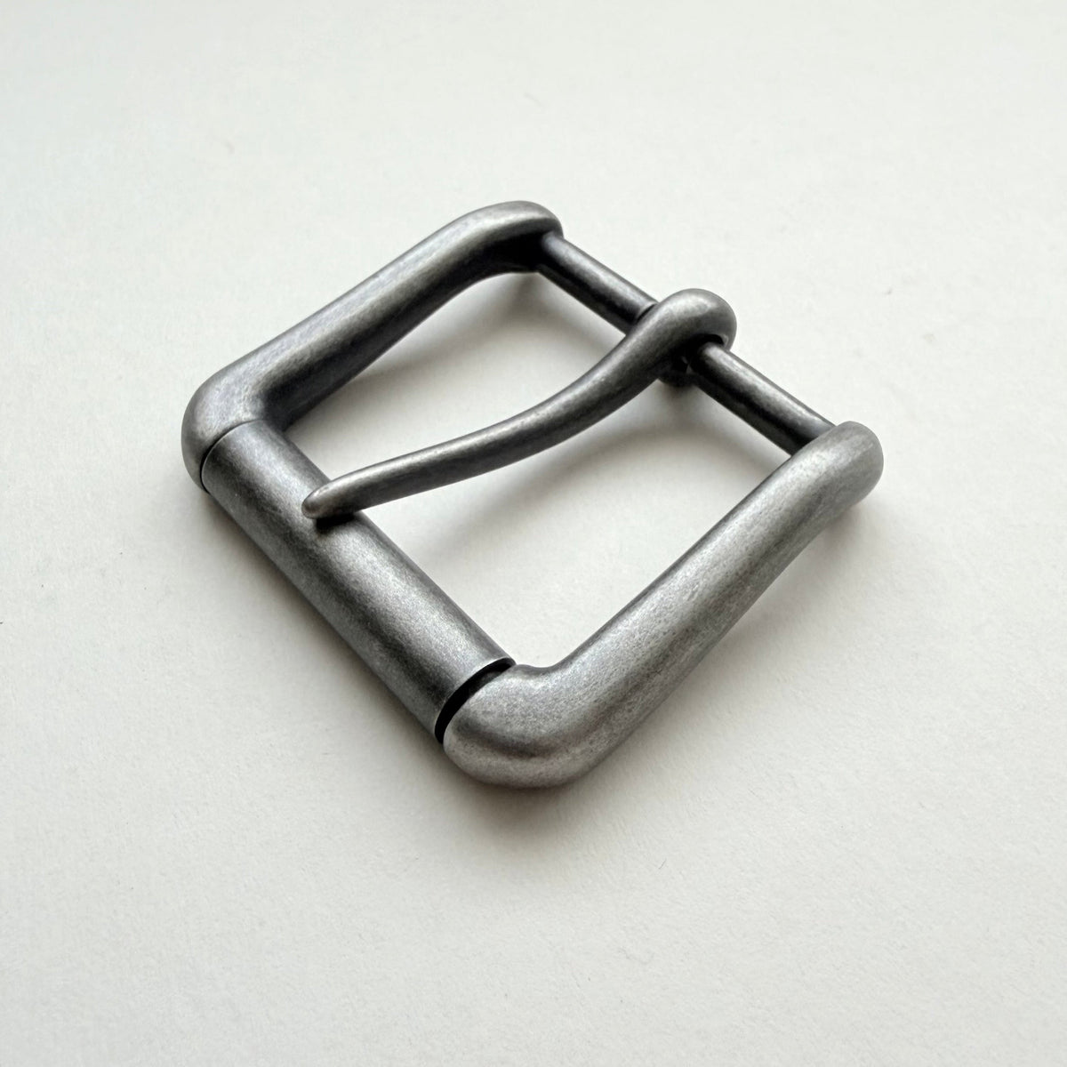 A single metal belt buckle with a rounded rectangular shape and a single prong, shown on a plain light background.