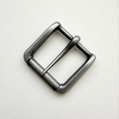 A single metal belt buckle with a square frame and single prong, finished in a dark gunmetal gray or antique silver tone, photographed on a plain off-white background.