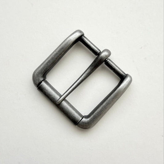 A single metal belt buckle with a square frame and single prong, finished in a dark gunmetal gray or antique silver tone, photographed on a plain off-white background.