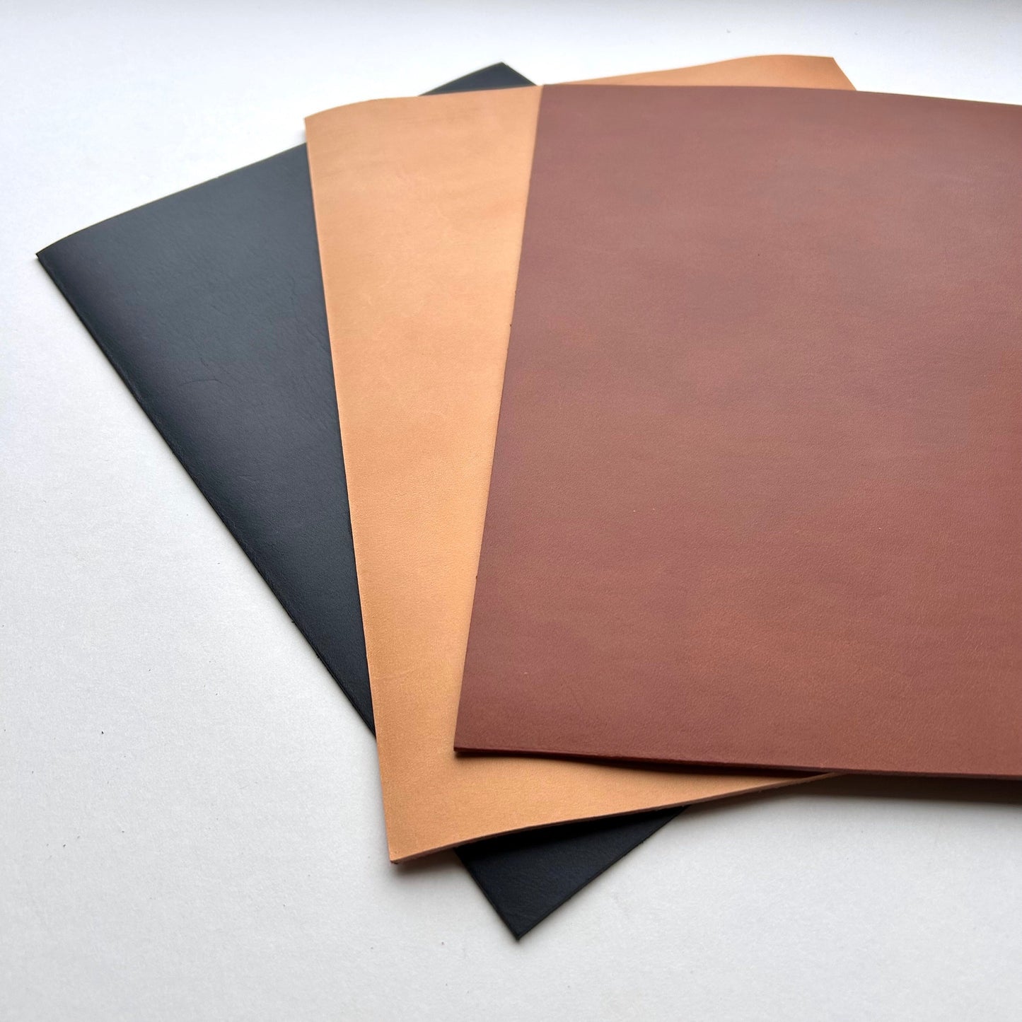 Three sheets of leather with different colors on a white background