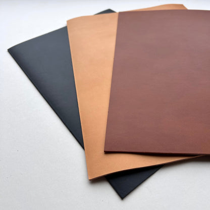 Three sheets of leather in black, brown, and beige on a white background