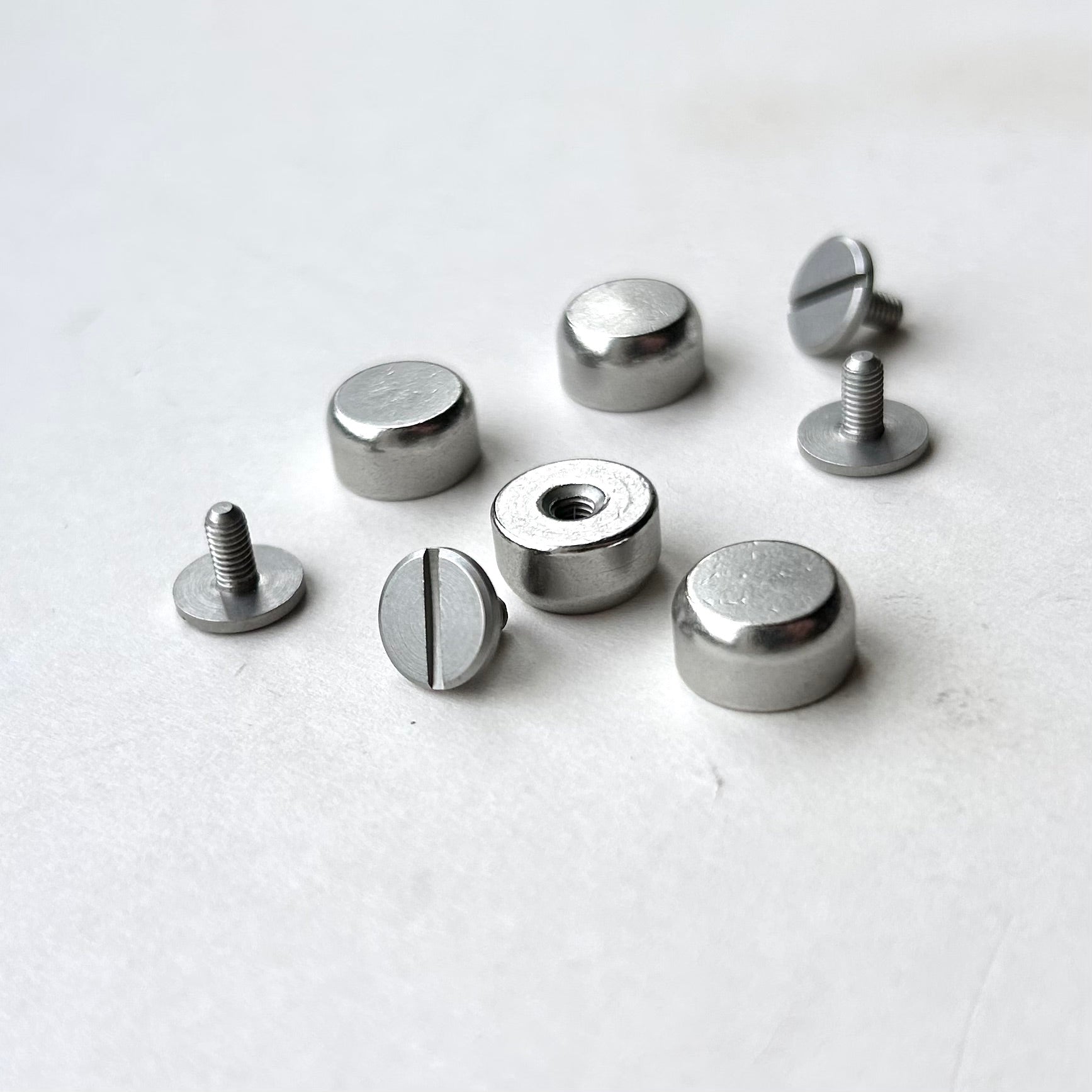Set of metal screw bag feet in silver on a white background