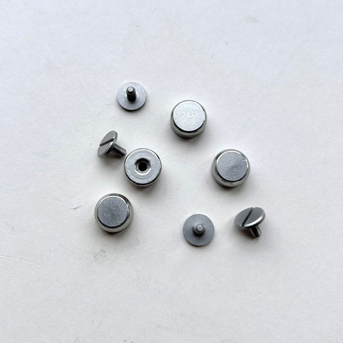 Set of metal screw bag feet in silver on a white background