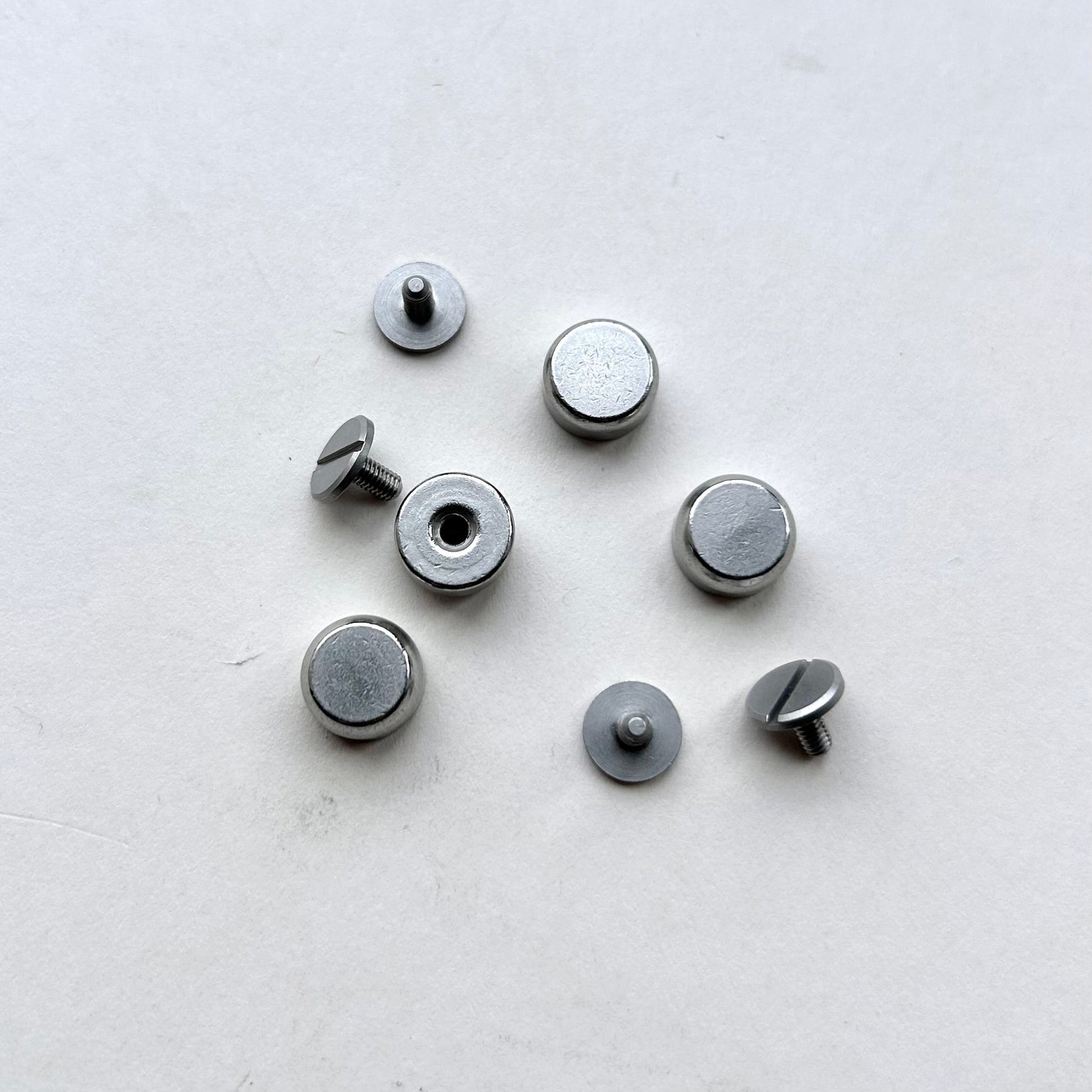 Set of metal screw bag feet in silver on a white background