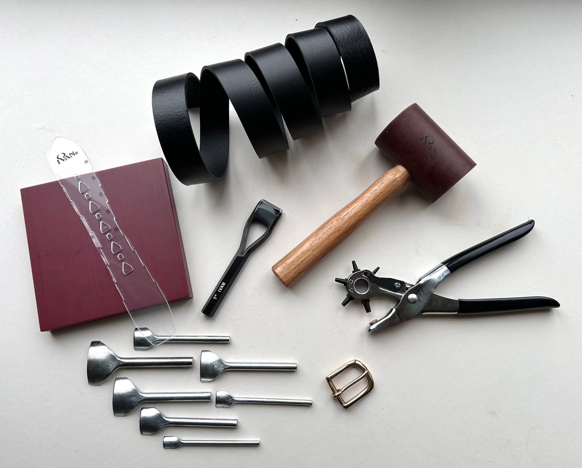 Collection of leatherworking tools on a white surface