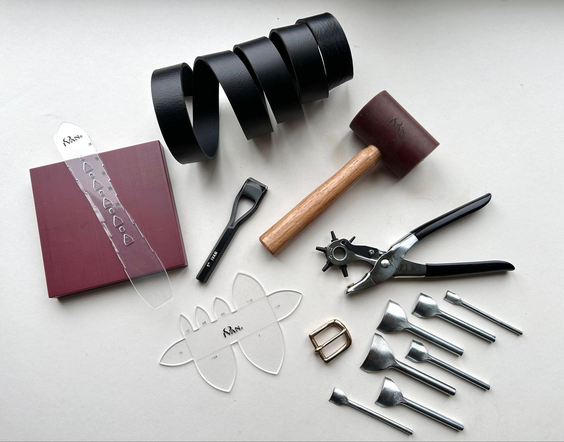 Collection of leatherworking tools and materials on a white surface